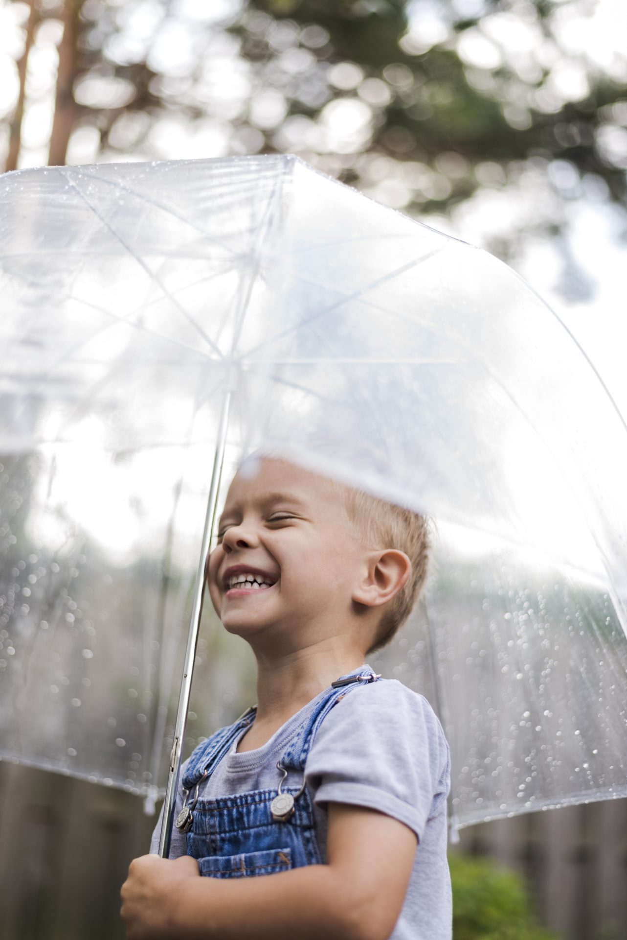 menino feliz segurando um guarda chuva enquanto esta de pe ao ar livre durante estacao chuvosa - Guarda-chuvas FGM